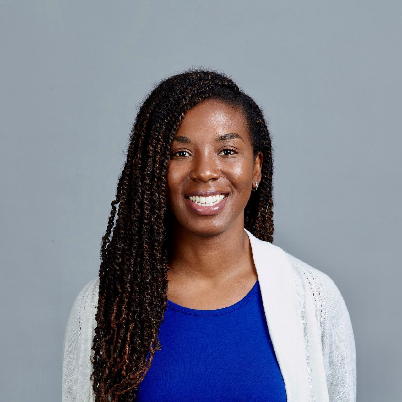 A woman wearing a blue shirt and a white cardigan is smiling for the camera.