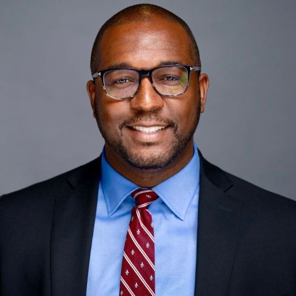 A man in a suit and tie is smiling for the camera