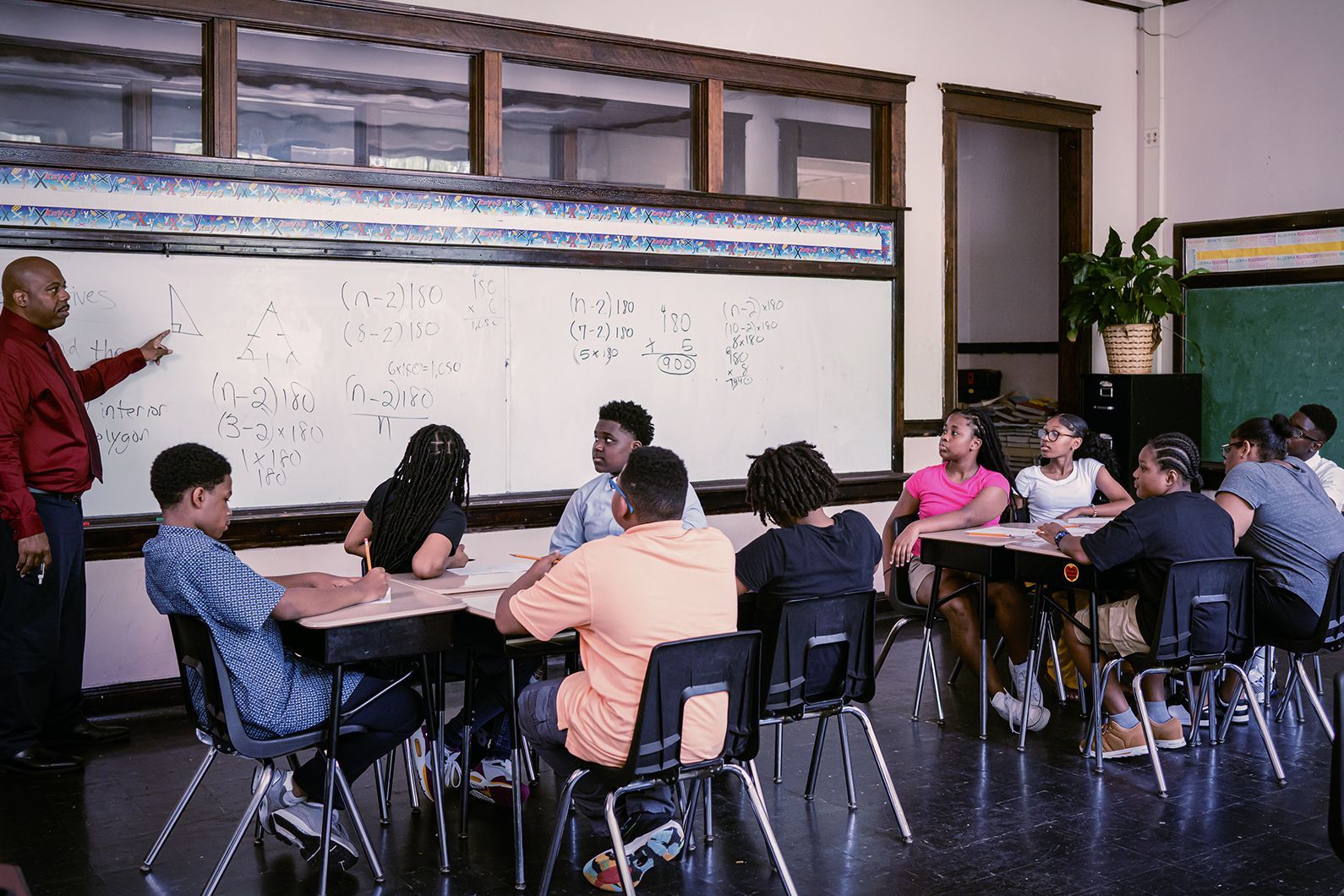 A man is teaching a group of children in a classroom.