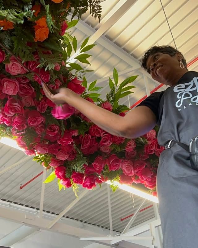 A woman in an apron is standing in front of a bunch of flowers