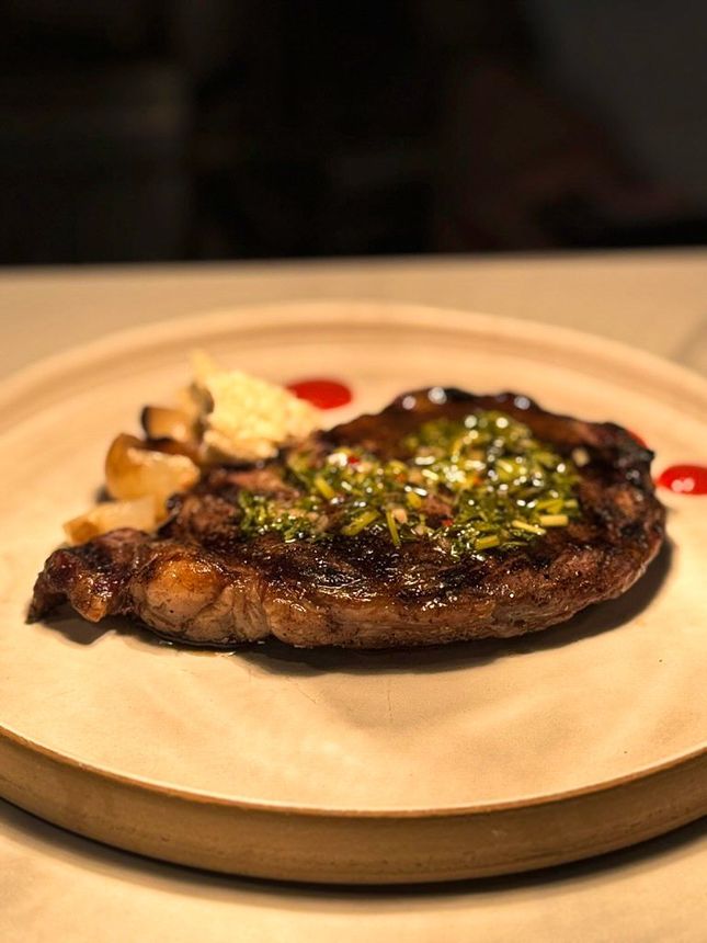 Plate with two crab cakes, a side of slaw in a round container, and sauces.