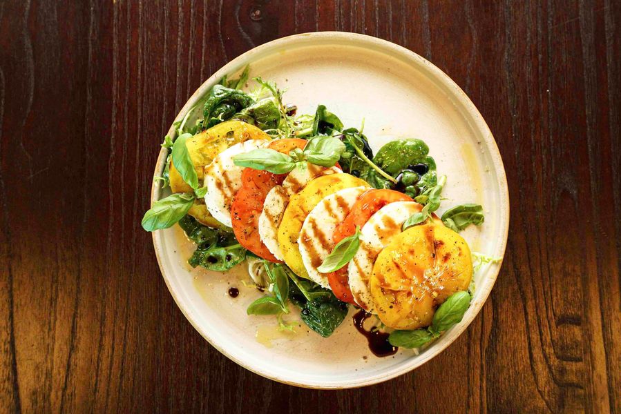 Chicken Caesar salad in a rustic bowl on a black tray.