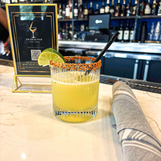 Cocktail with lime and chili rim on a bar counter.
