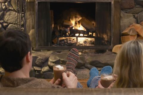 couple drinking cocoa in front of stone fireplace