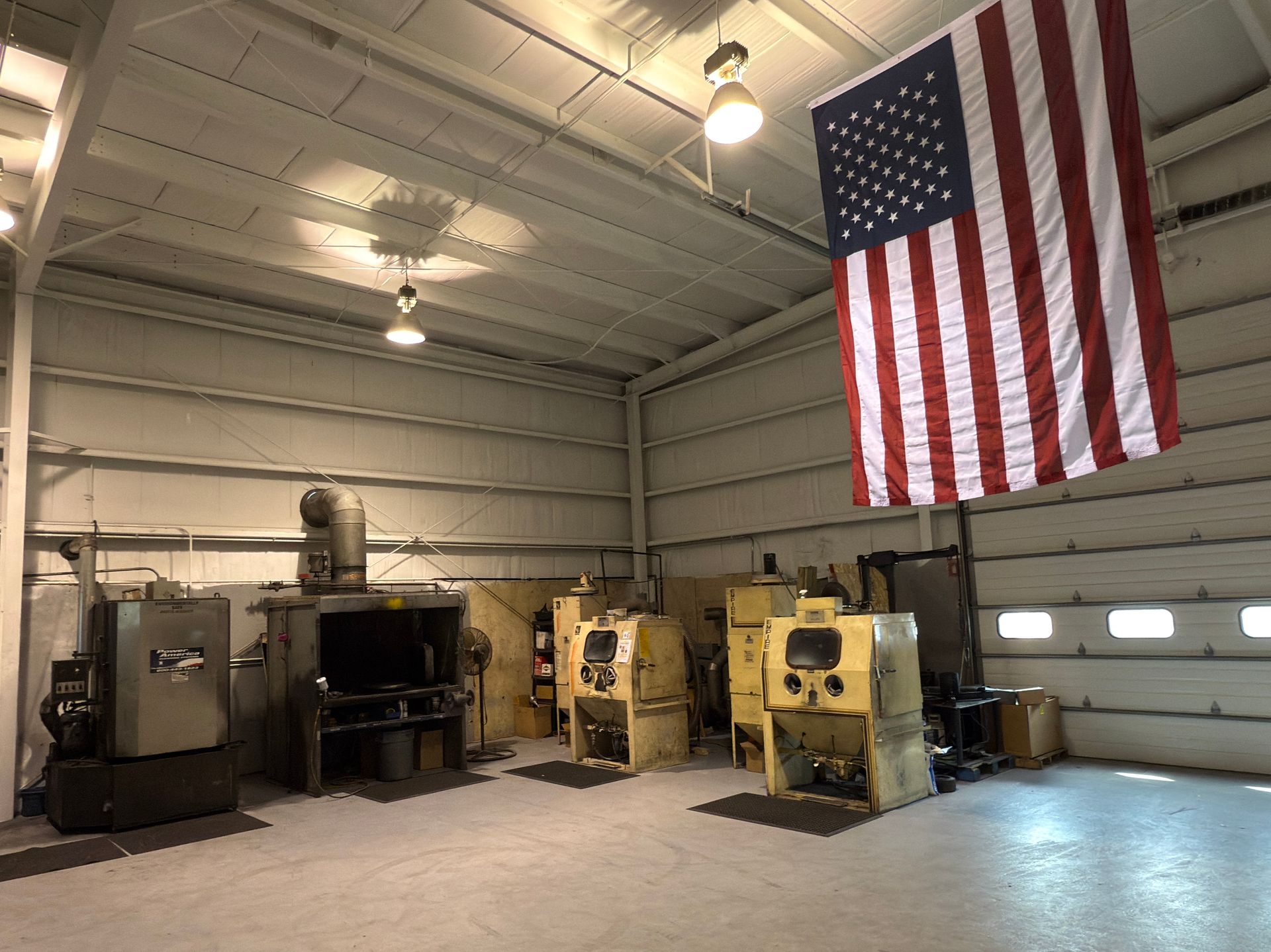 A large american flag hangs from the ceiling of a factory