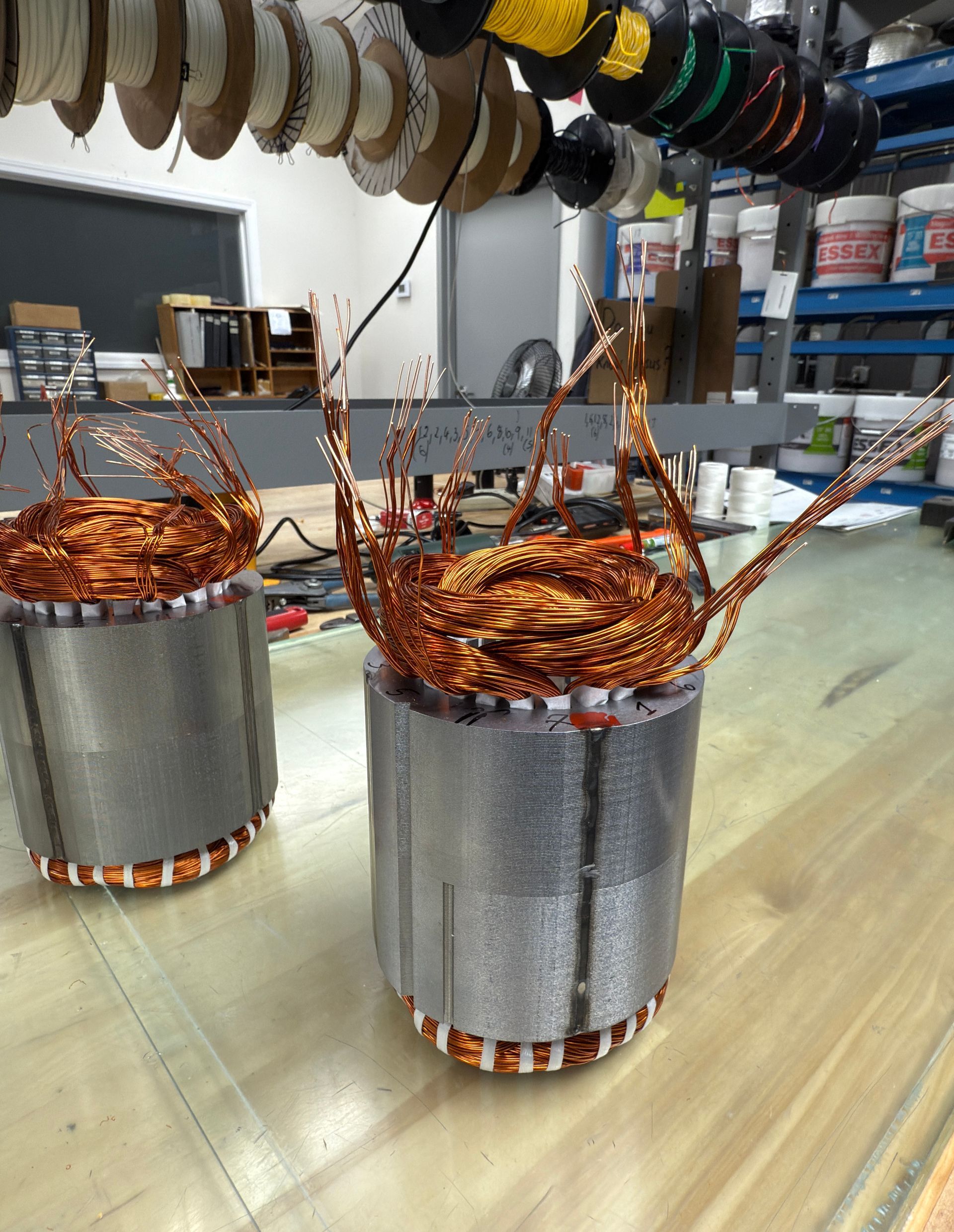 Two metal cylinders with copper wires coming out of them are sitting on a wooden table.