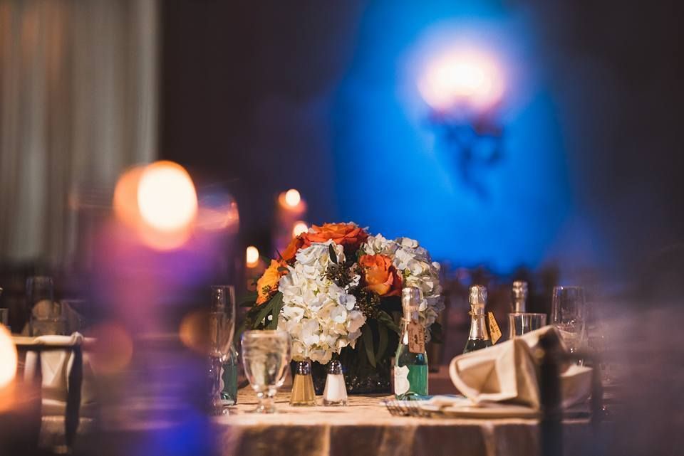 Elegant banquet table with a floral centerpiece, candles, and soft blue and purple ambient lighting