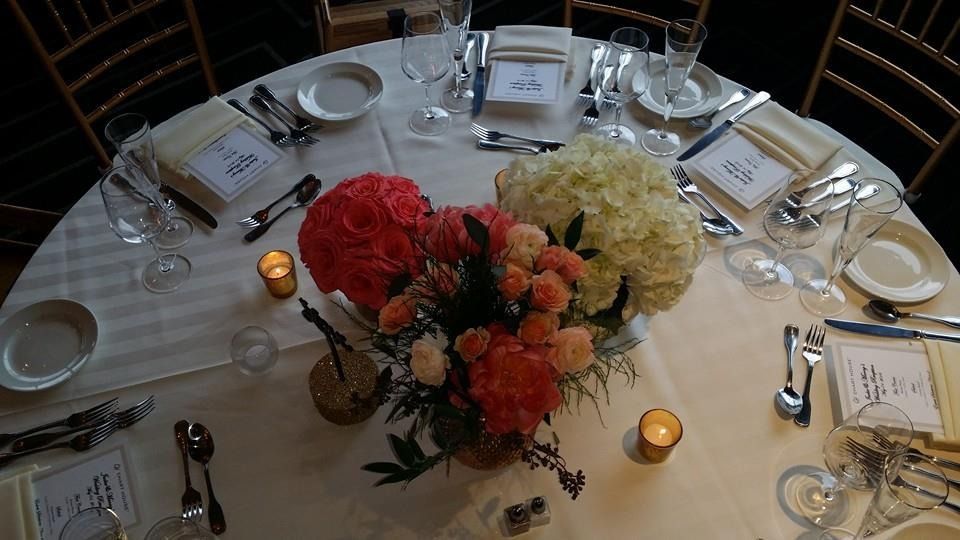 Elegant round banquet table set with floral centerpiece, candles, wine glasses, and place cards