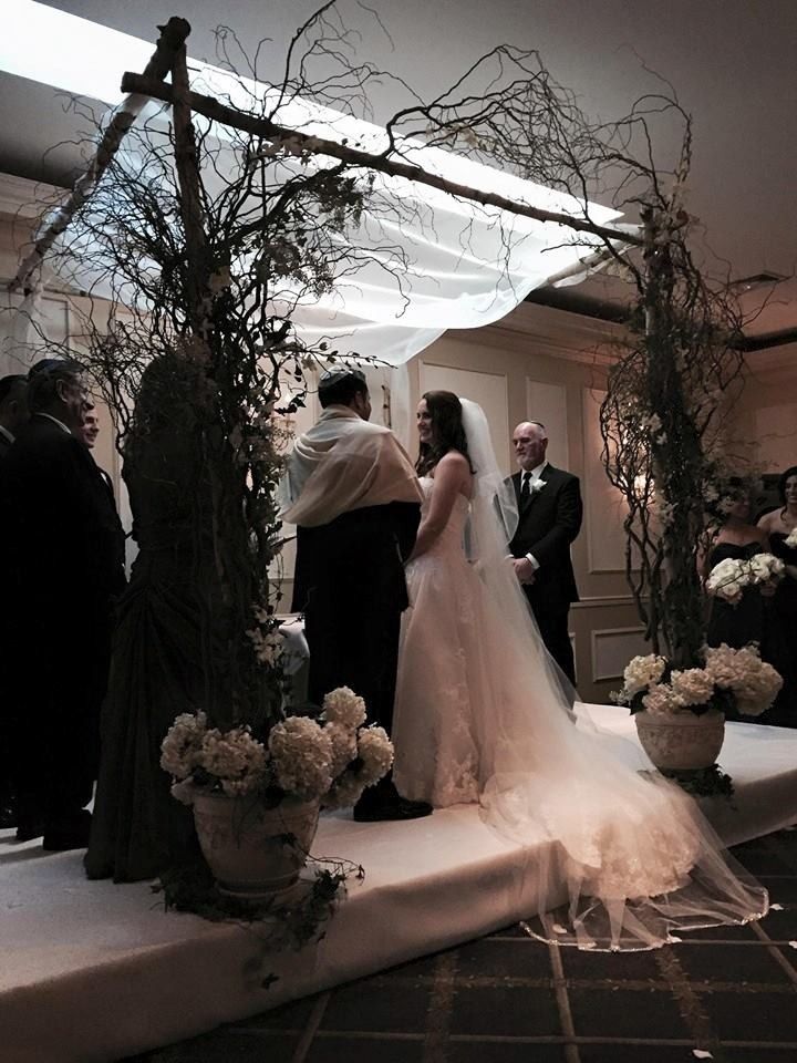 Outdoor wedding ceremony under a white canopy with bride in a long veil and guests standing nearby
