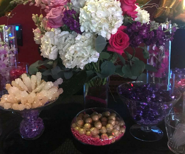 Decorative floral arrangement with white, pink, and purple flowers on a table, plus glass bowls of ornaments