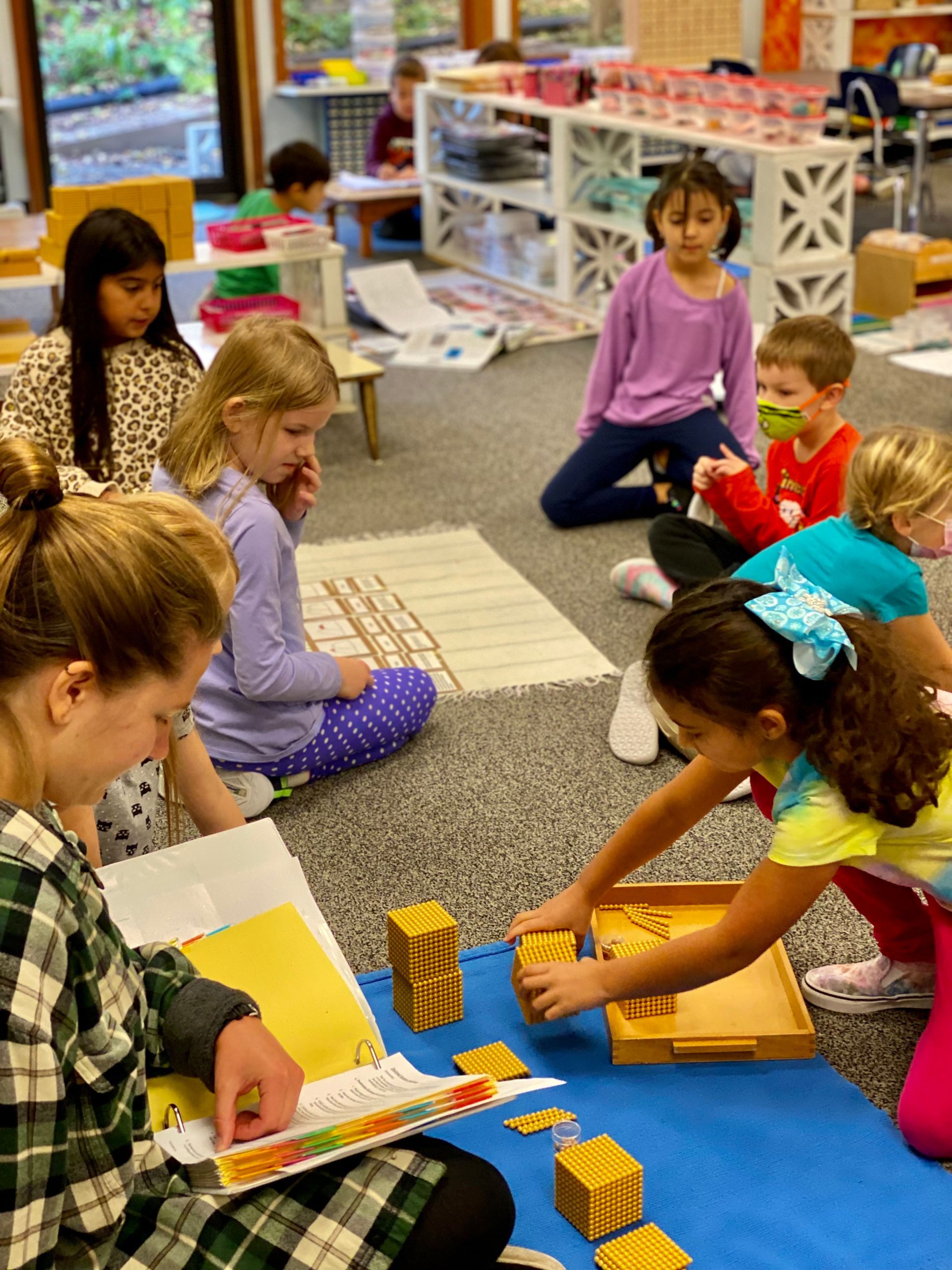 Montessori guide and children working in the classroom