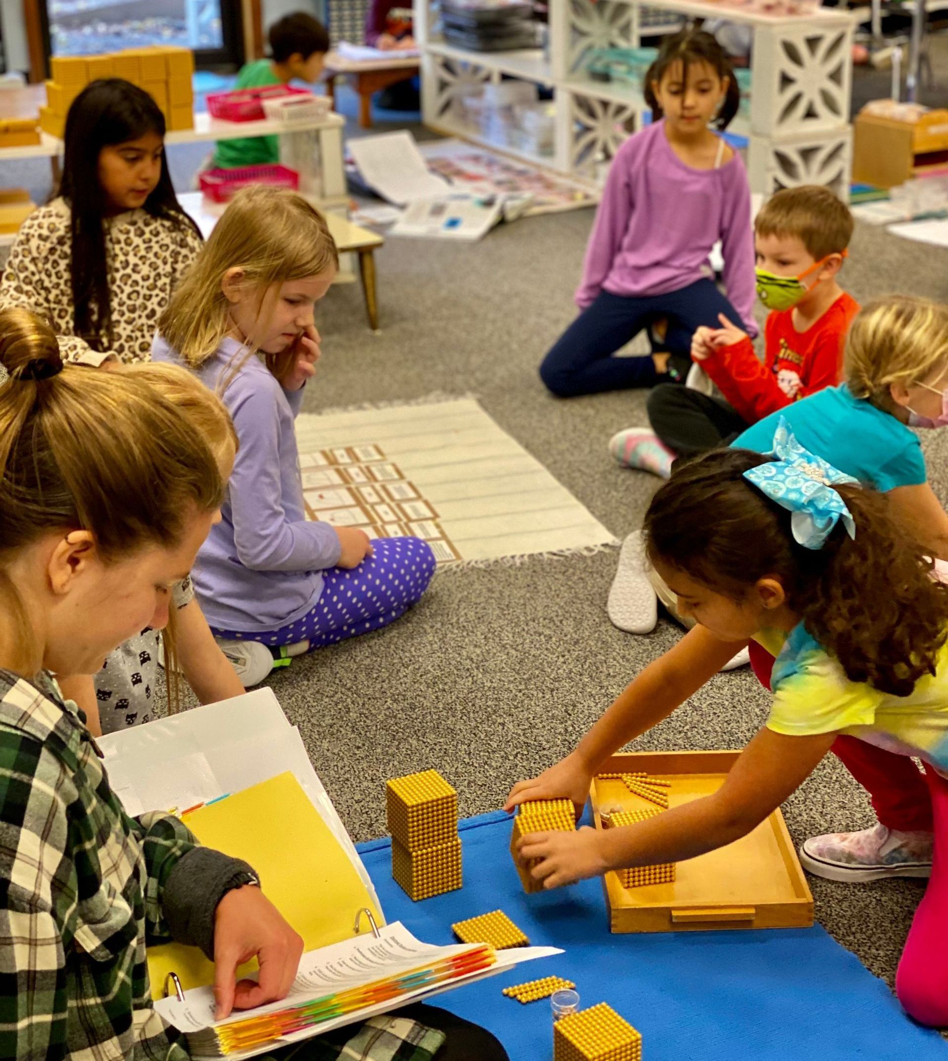 Montessori guide and children working in the classroom