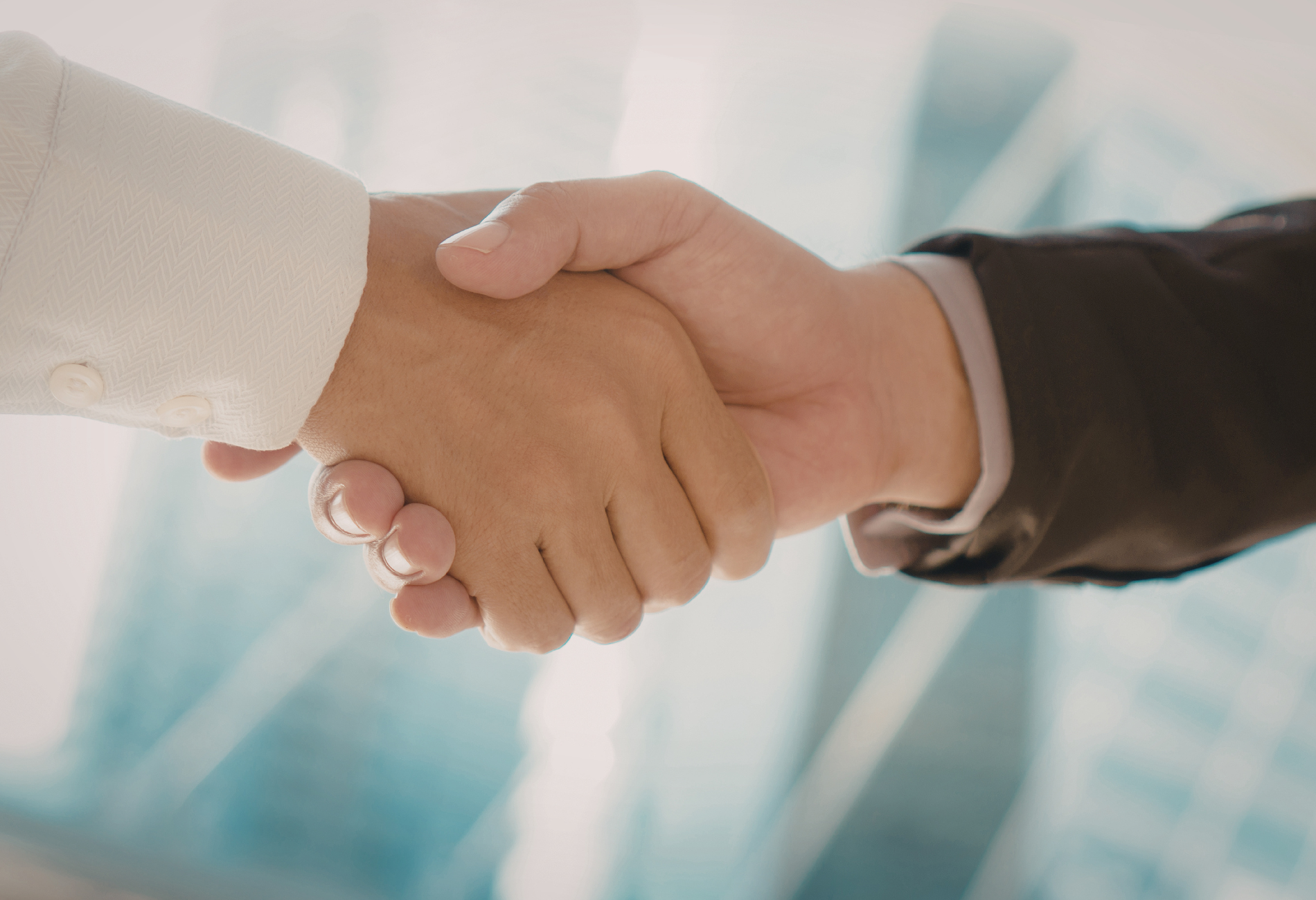Close-up of two hands shaking, against a blurred cityscape.