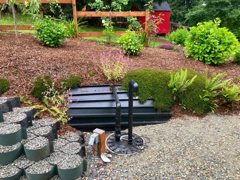 A garden with a fence and a red shed in the background