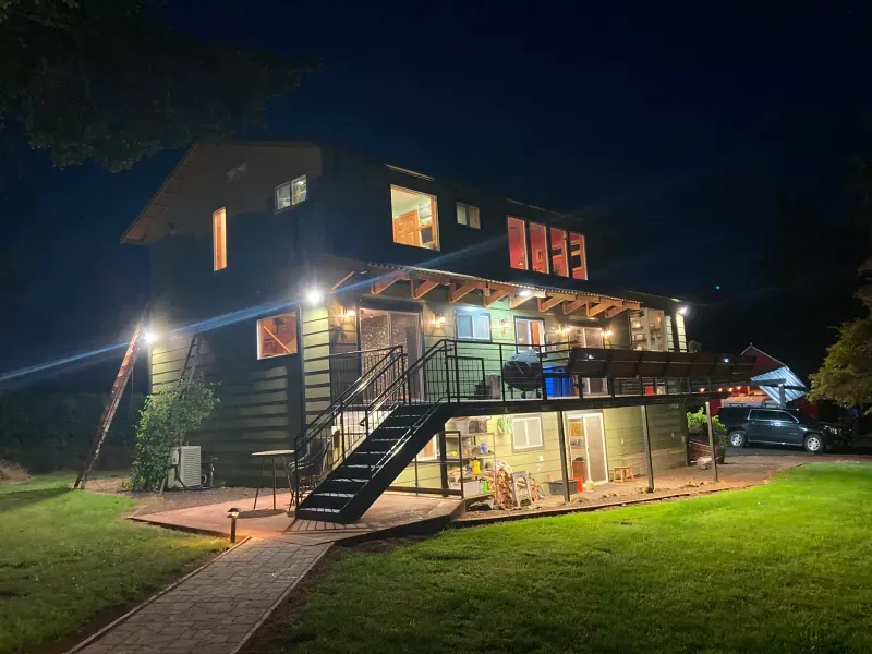 A large house with stairs leading up to the second floor is lit up at night.