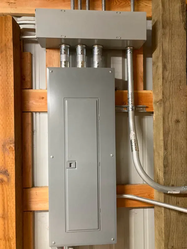 A gray electrical box is hanging on a wooden wall.