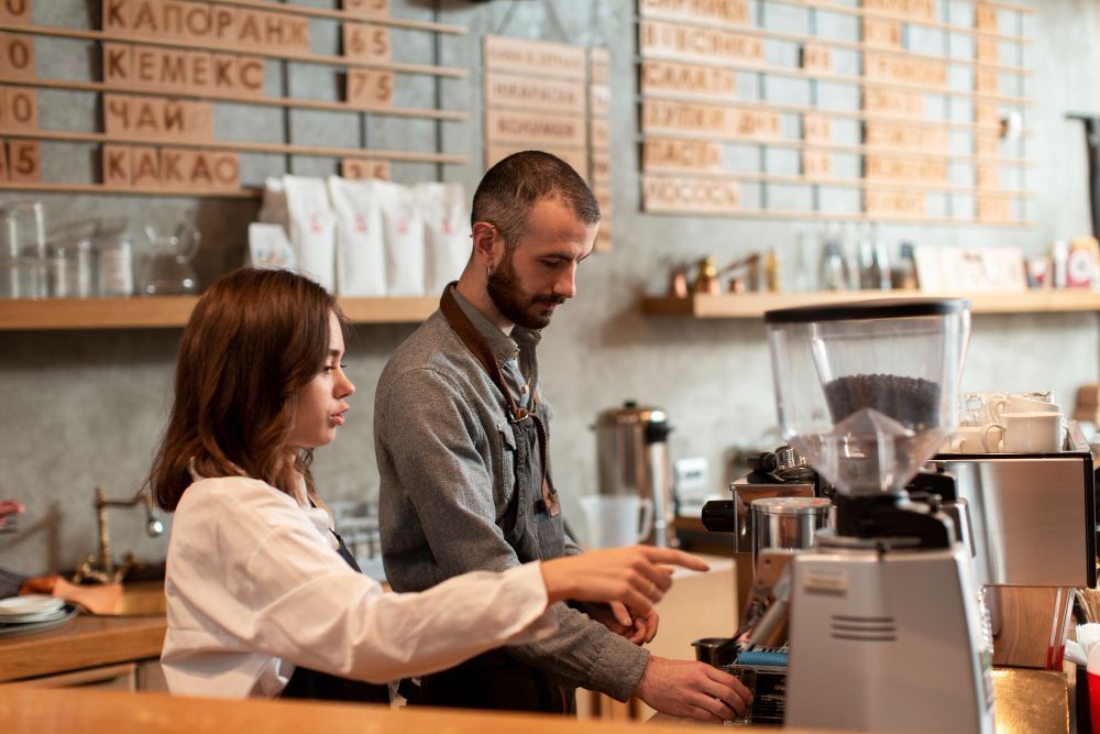 A man and a woman are working in a coffee shop.