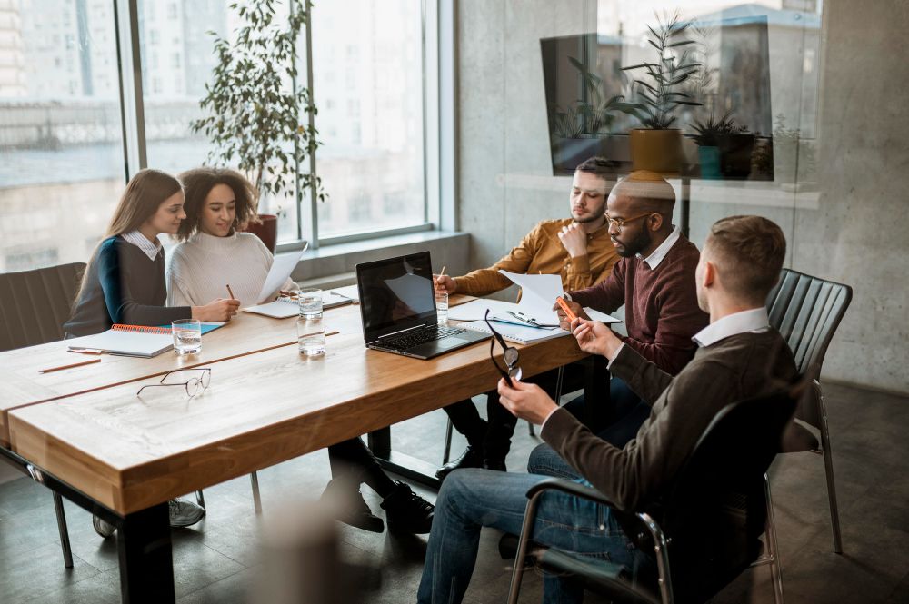 A group of people are sitting around a table having a meeting.