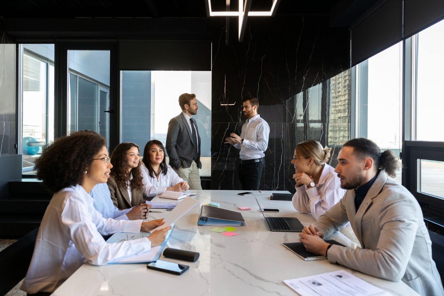 A group of people are sitting around a table in a conference room having a meeting.