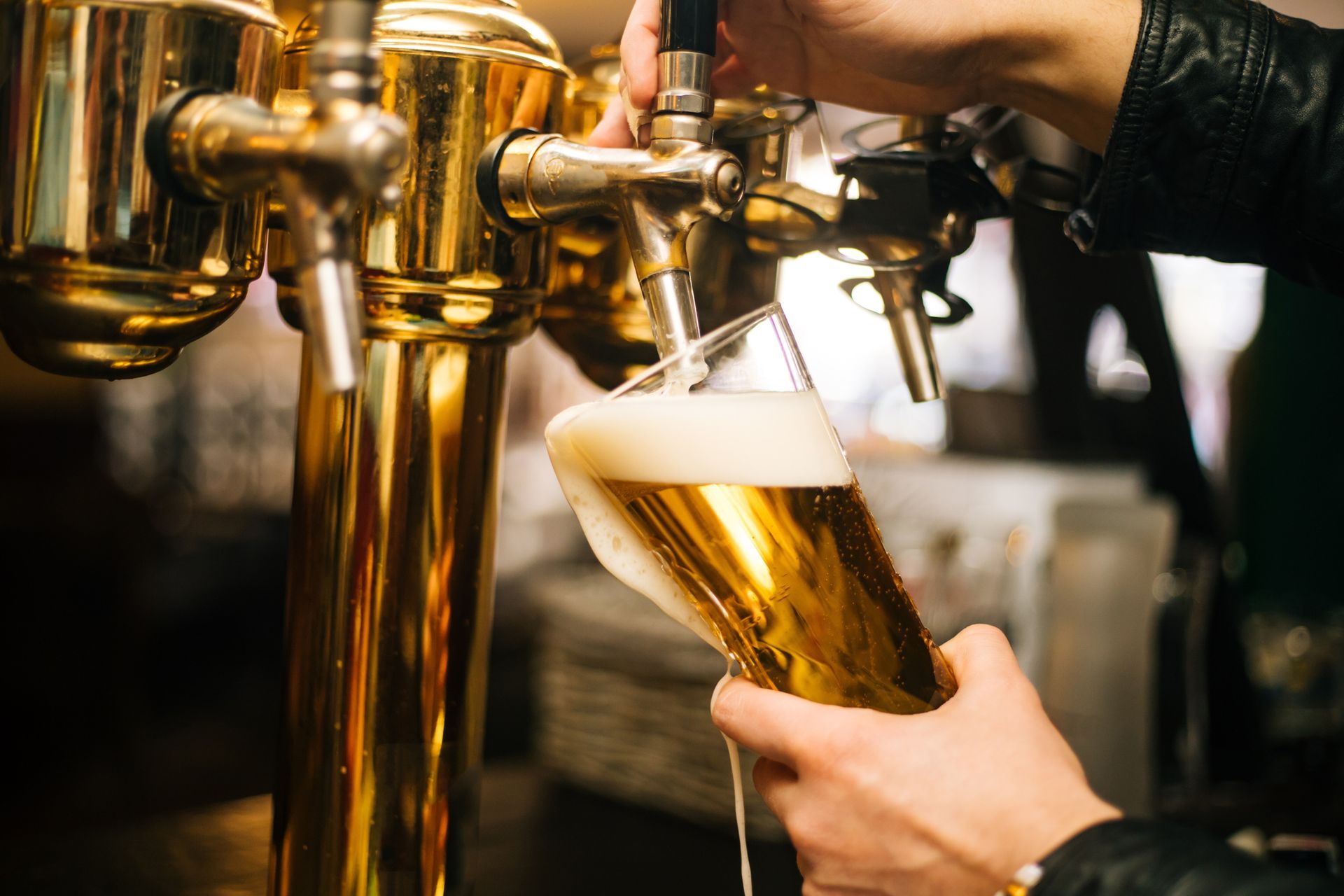 A person is pouring beer from a tap into a glass.