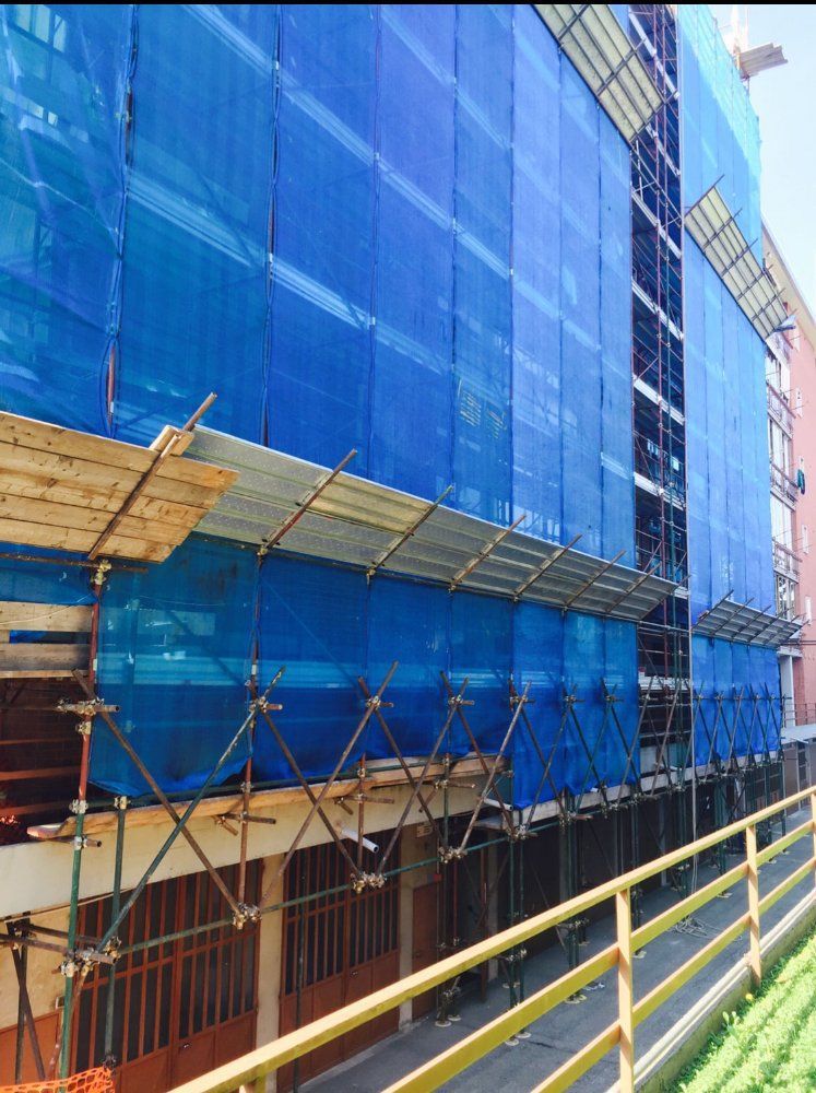 Un edificio in costruzione con impalcature blu sul lato