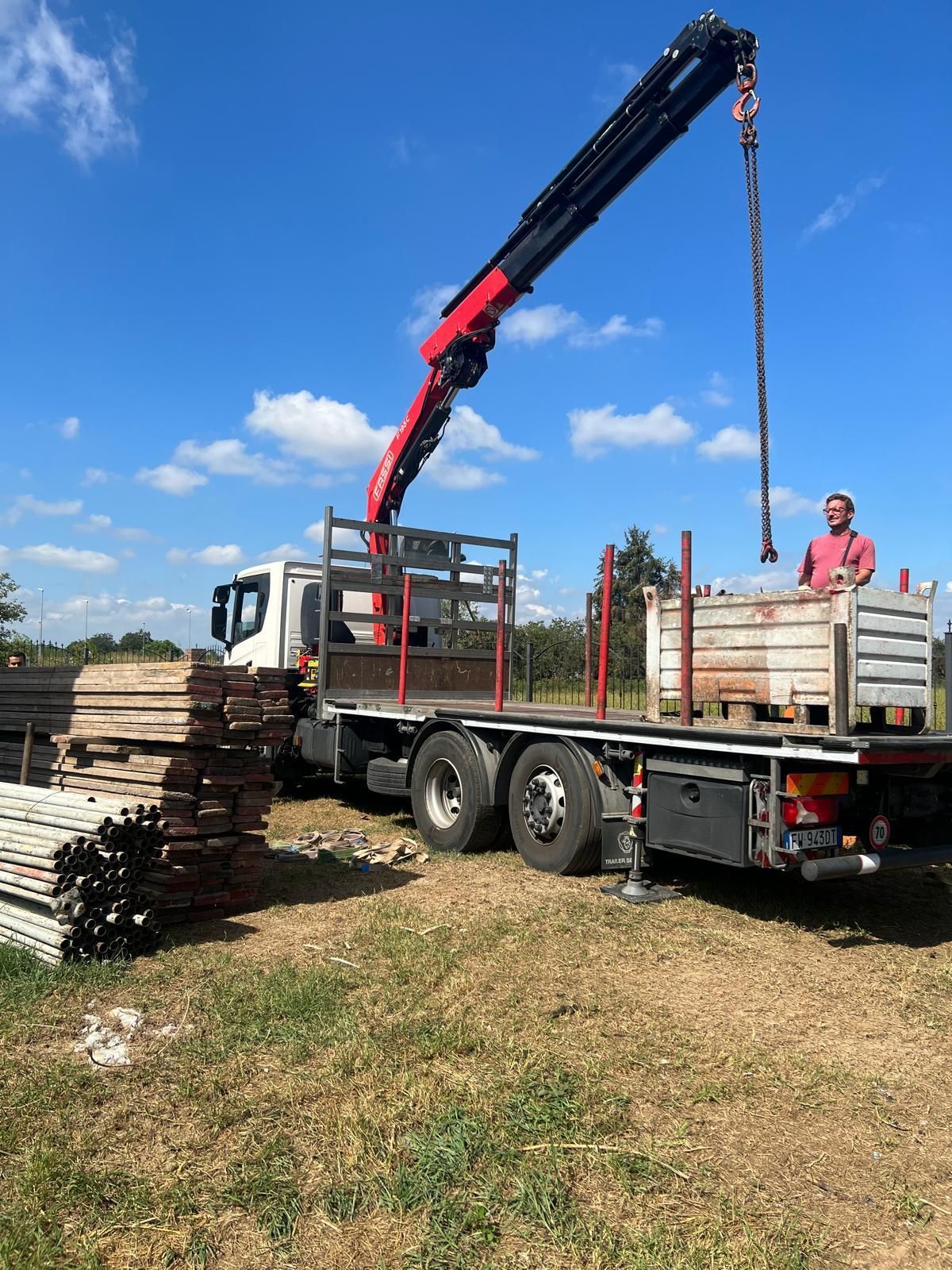 Un uomo è in piedi sul retro di un camion a cui è attaccata una gru.