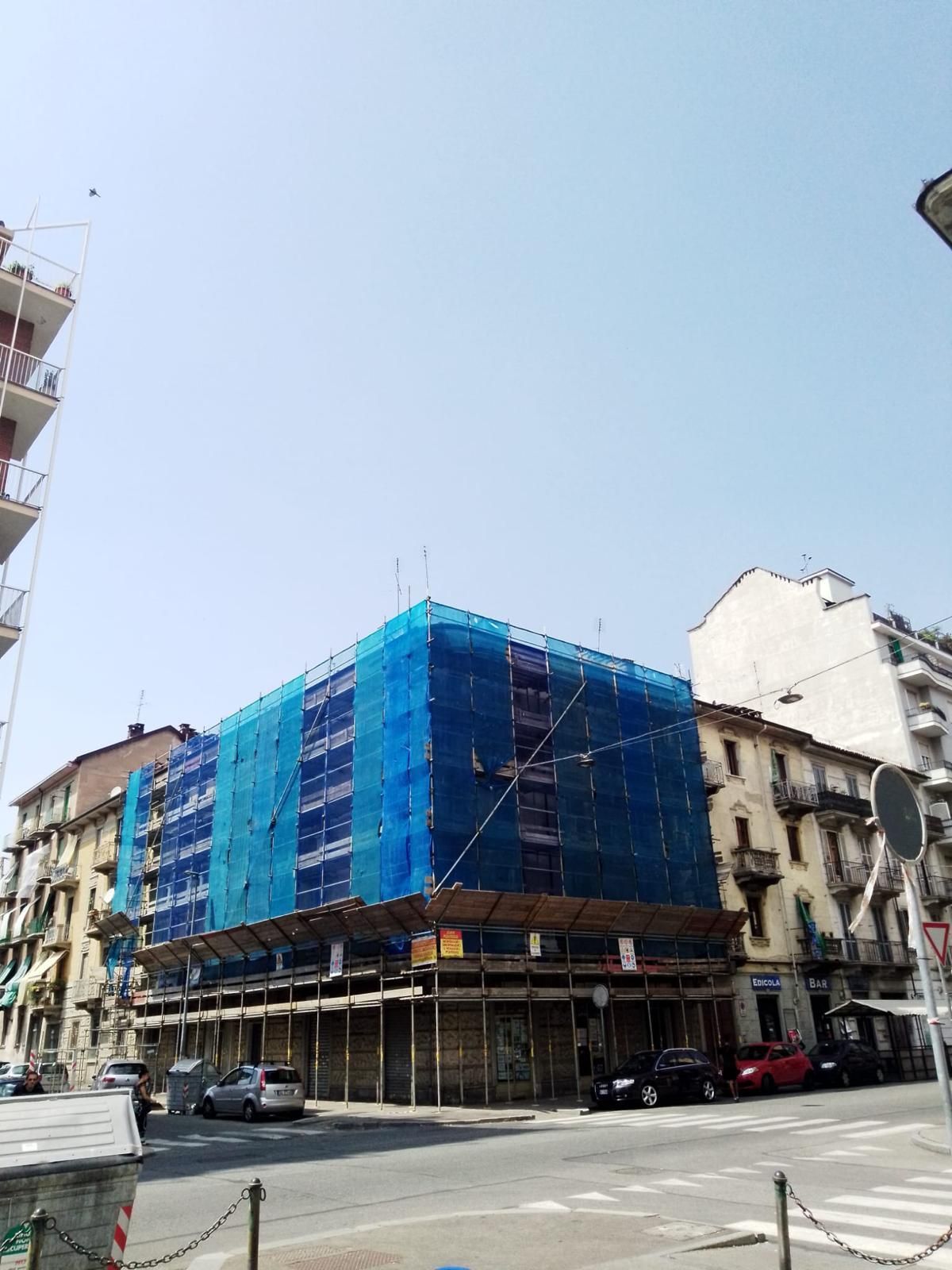 Un grande edificio è coperto da impalcature blu.