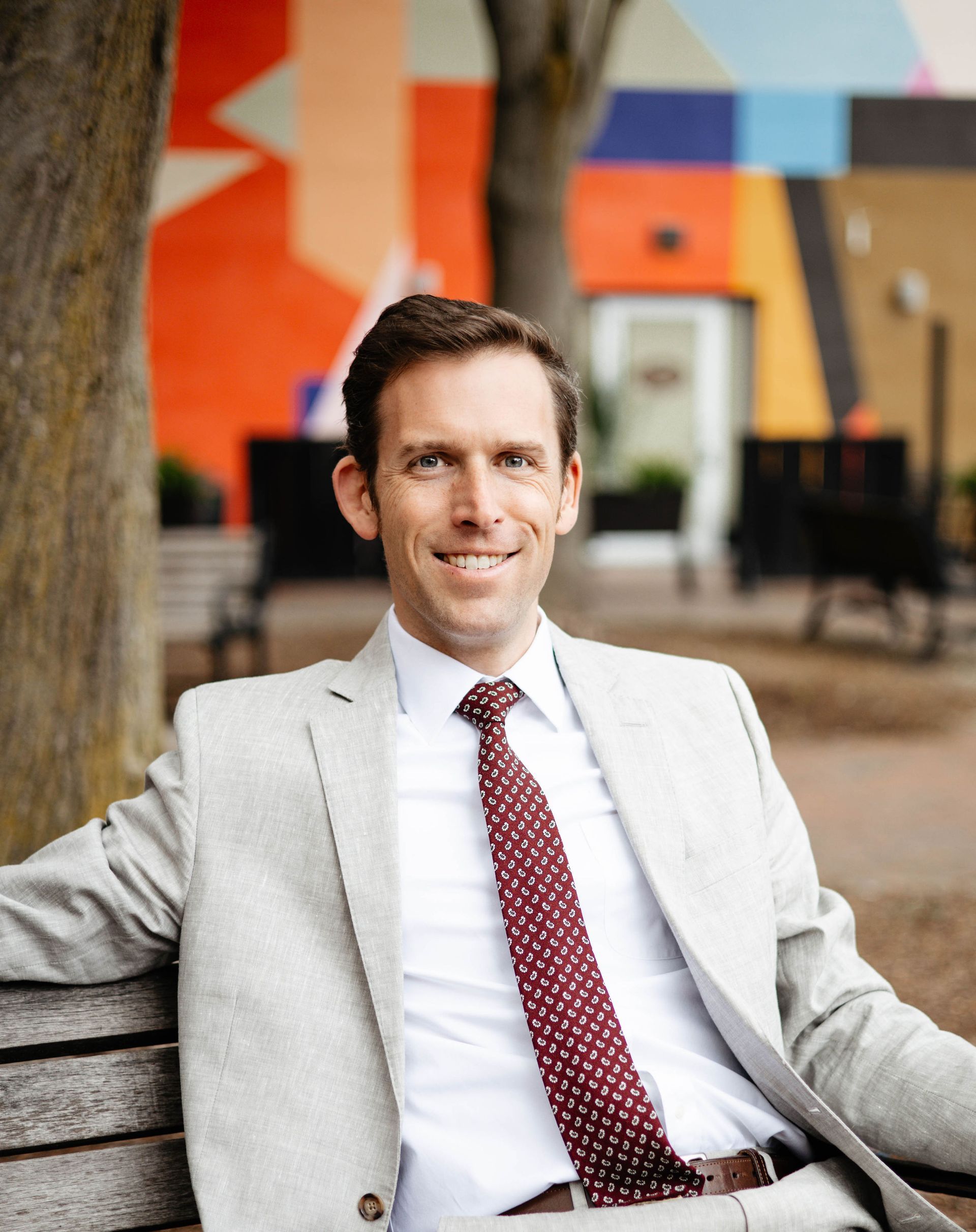 A man in a suit and tie is sitting on a bench