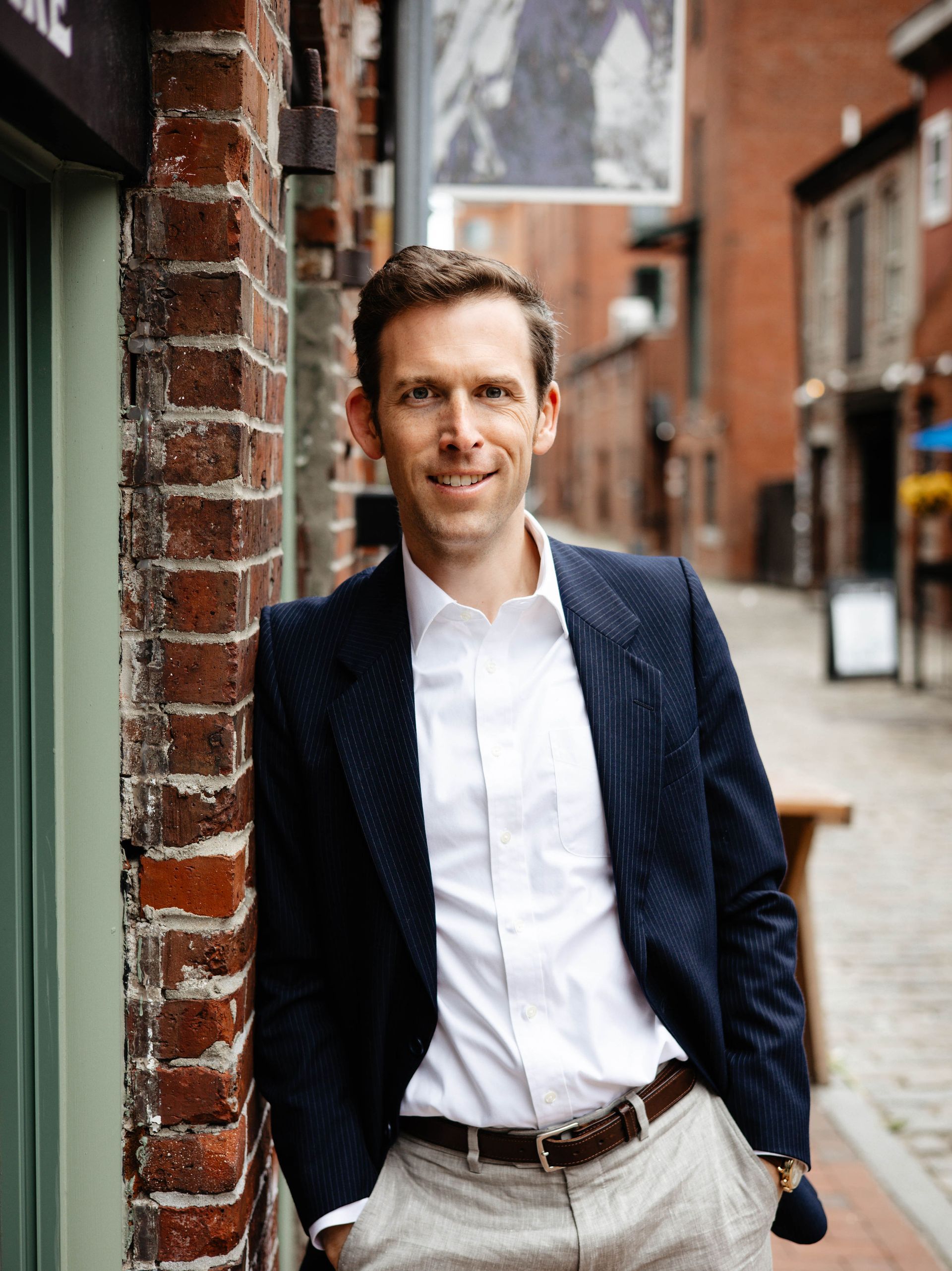 A man in a suit is leaning against a brick wall