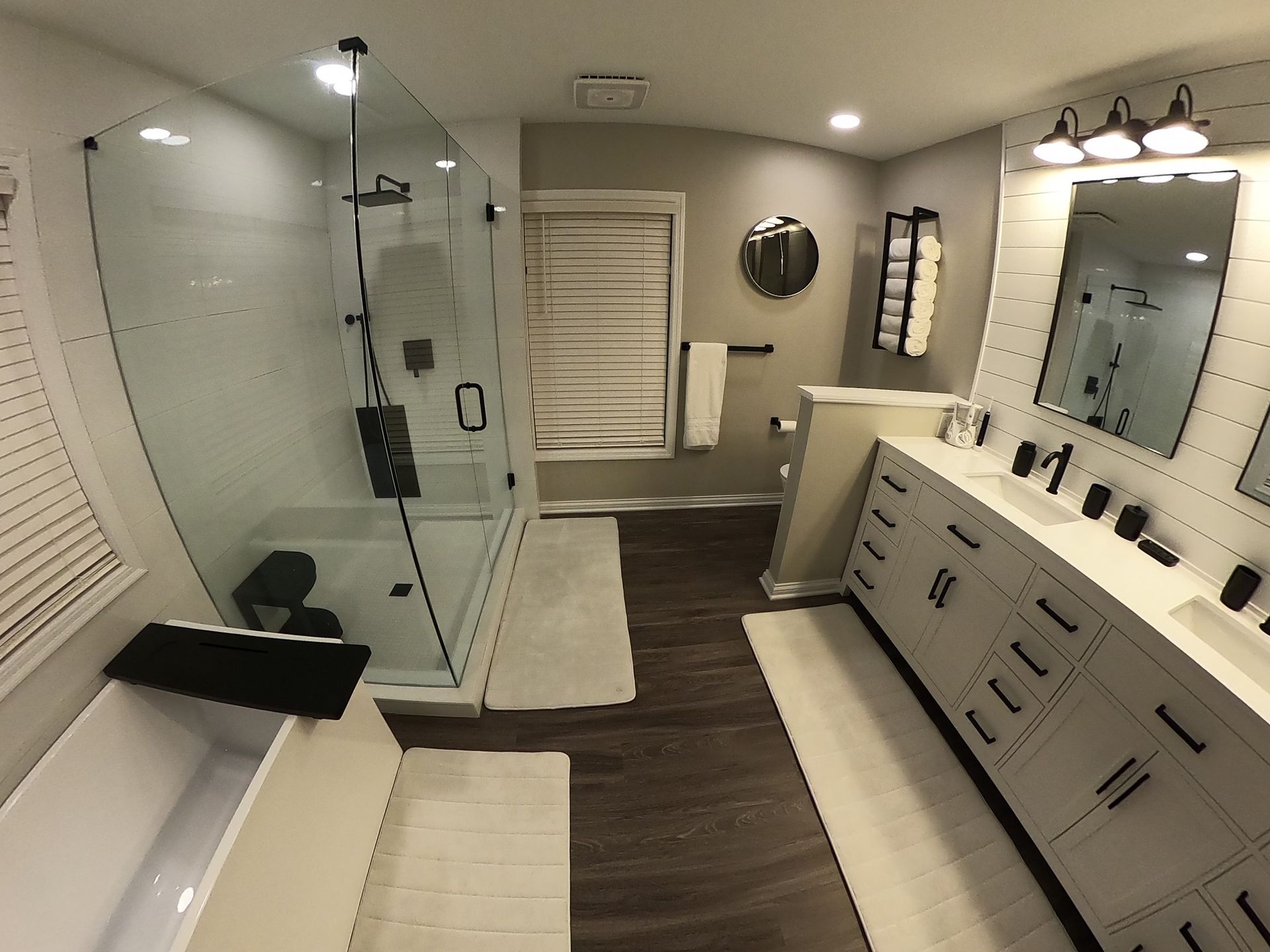 Modern bathroom with a shower, vanity, and soaking tub. White and dark wood accents.
