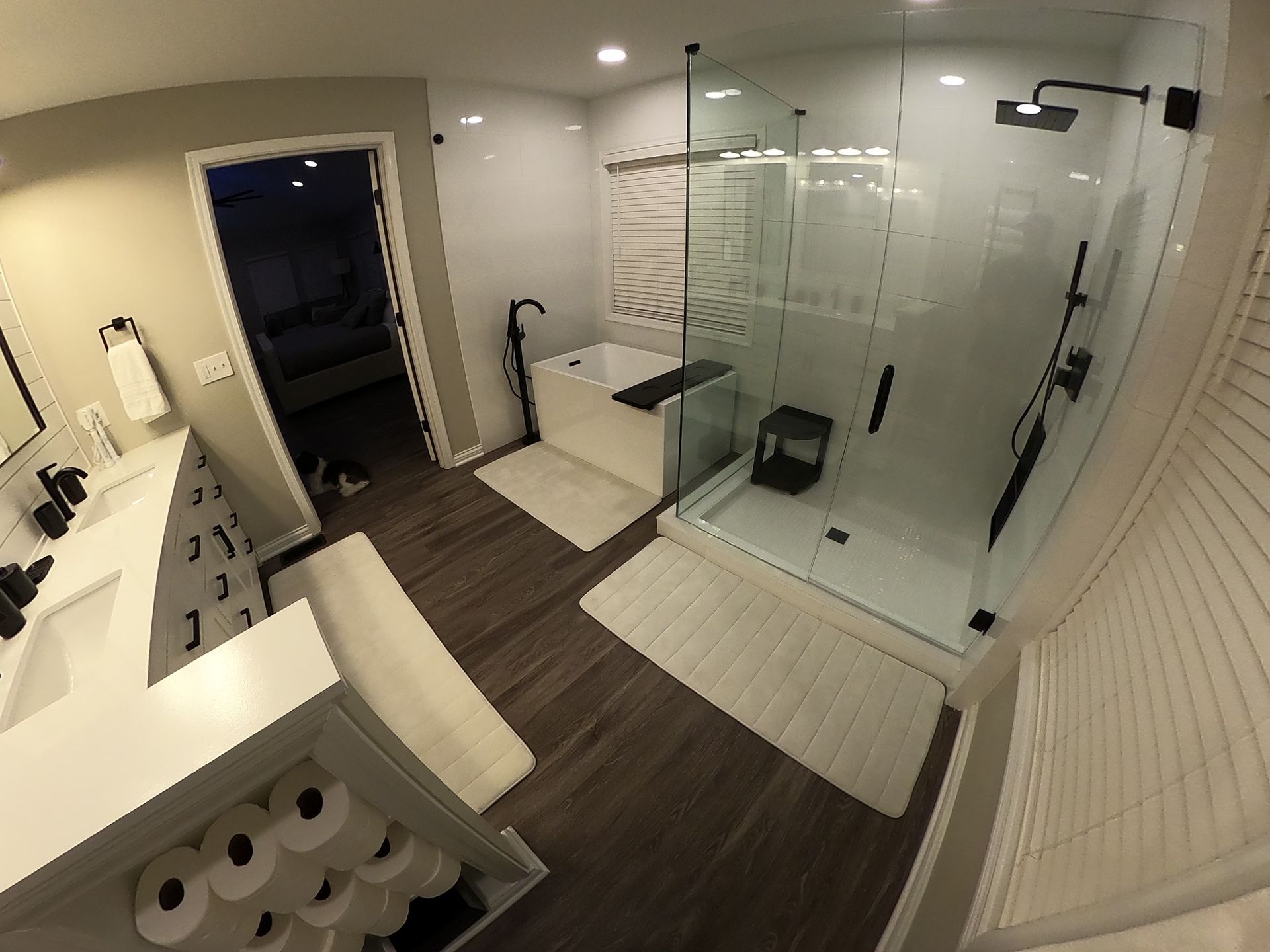 Modern bathroom with a walk-in shower, soaking tub, white cabinetry, and dark fixtures.