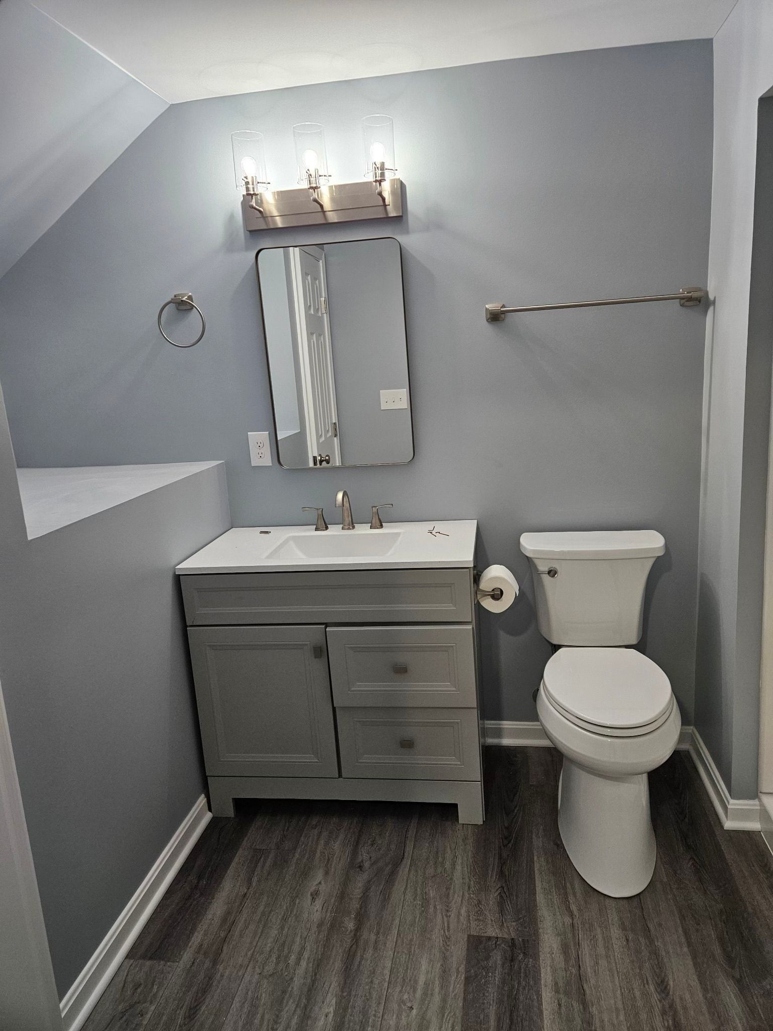 Gray bathroom with vanity, toilet, and mirror; a modern aesthetic.