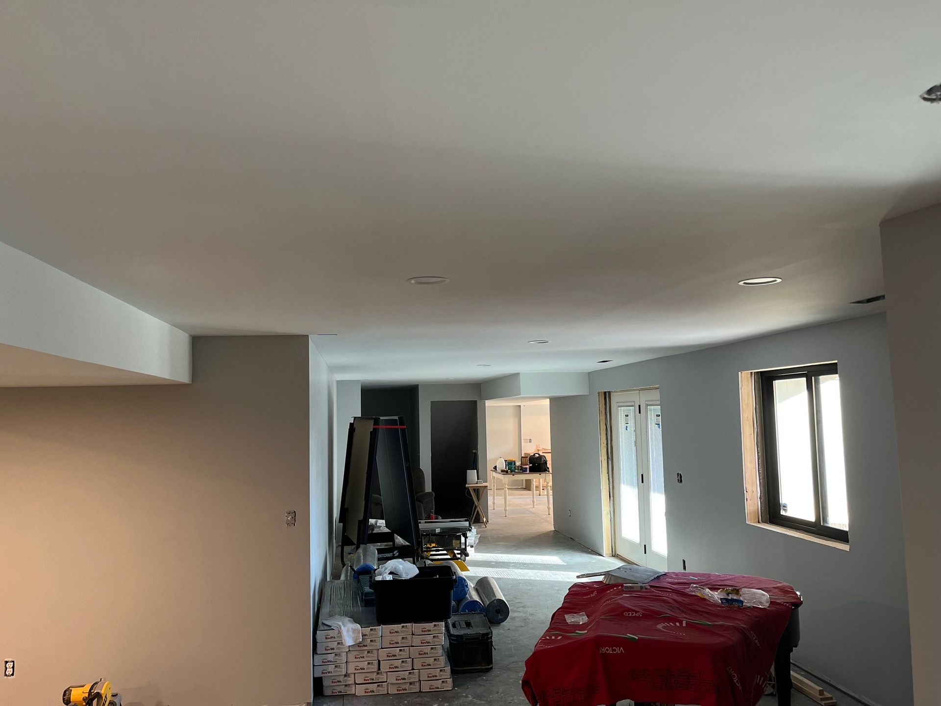 A partially renovated room with gray walls, white ceiling, and a red-covered object on the floor.