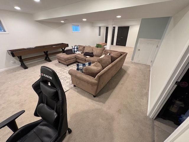 Basement living space with sofa, shuffleboard, gaming chair, and dark doors.