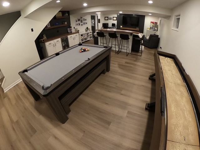 Game room with pool table, shuffleboard, bar, and seating.