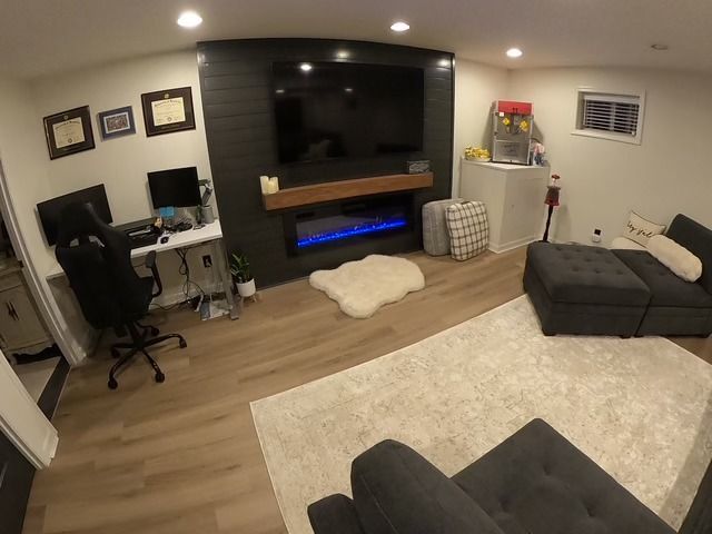 Cozy modern living room with dark accent wall, fireplace, large TV, and sectional sofa.