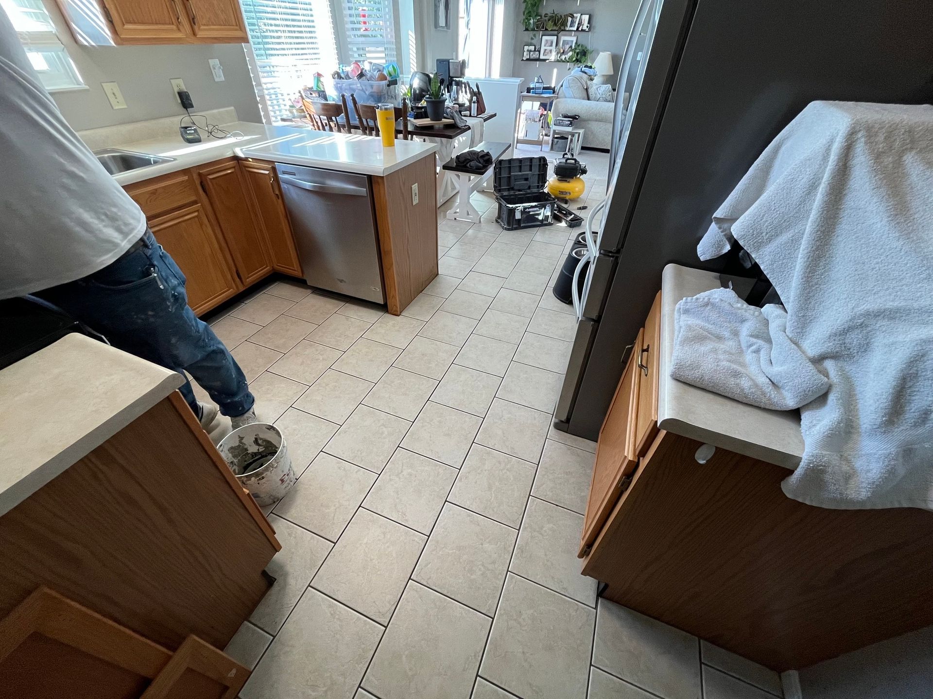 Person in a kitchen with wood cabinets, tile floor, and a dishwasher.