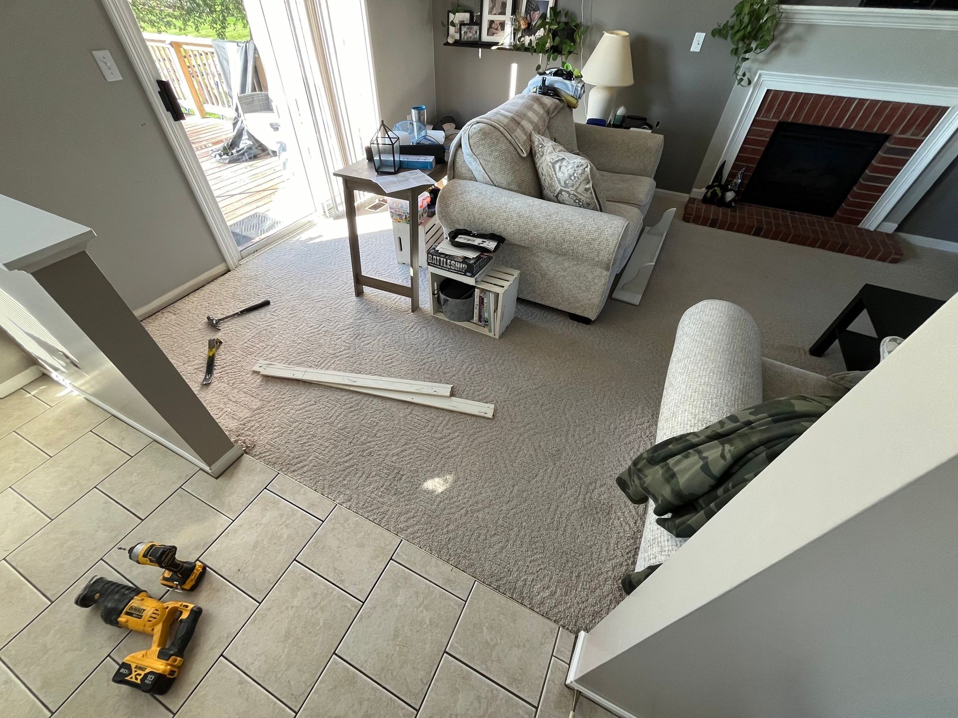 Living room with partially installed flooring, tools, and furniture.