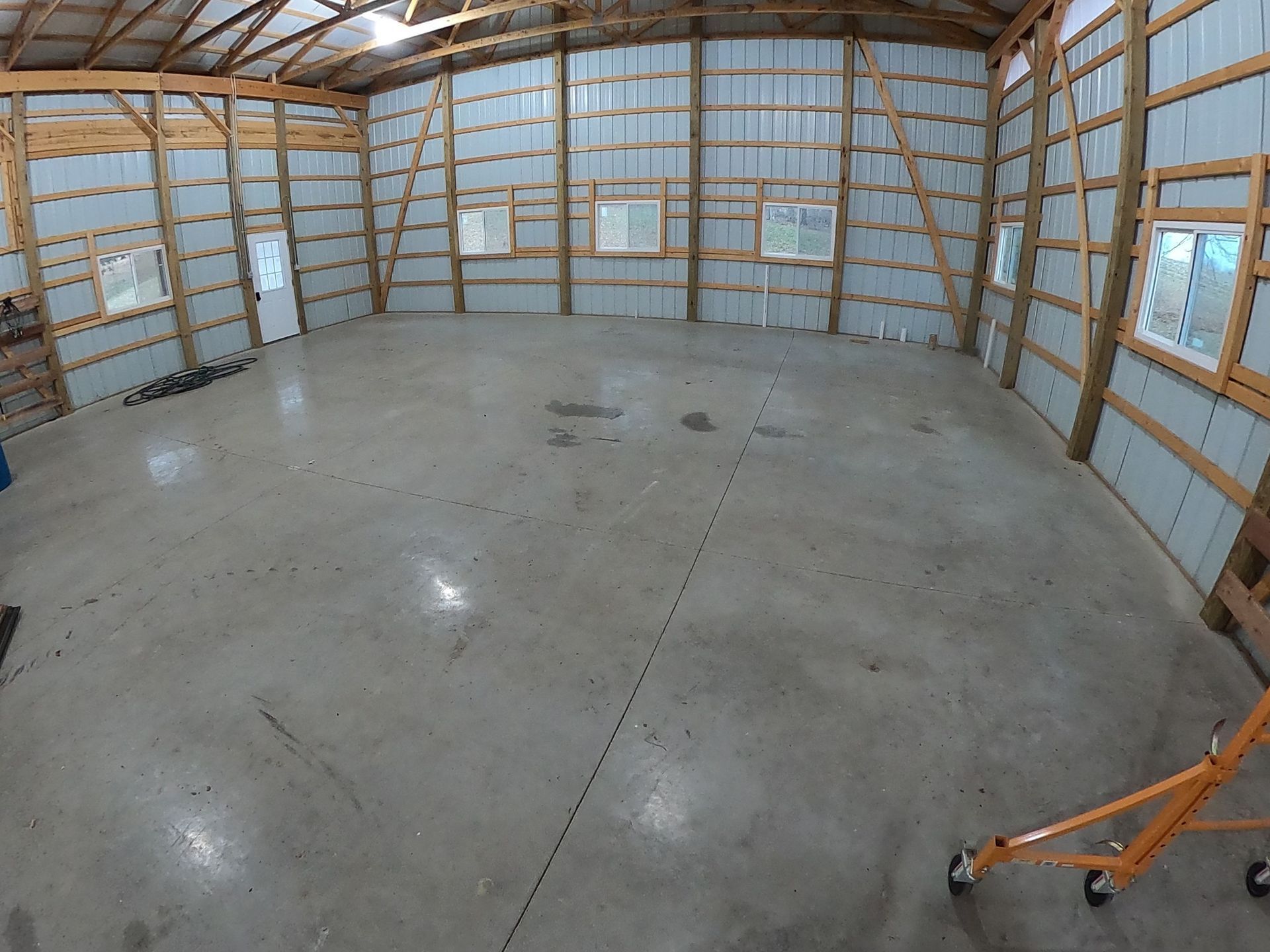 Empty metal and wood framed interior of a building. Grey concrete floor, windows and doors.