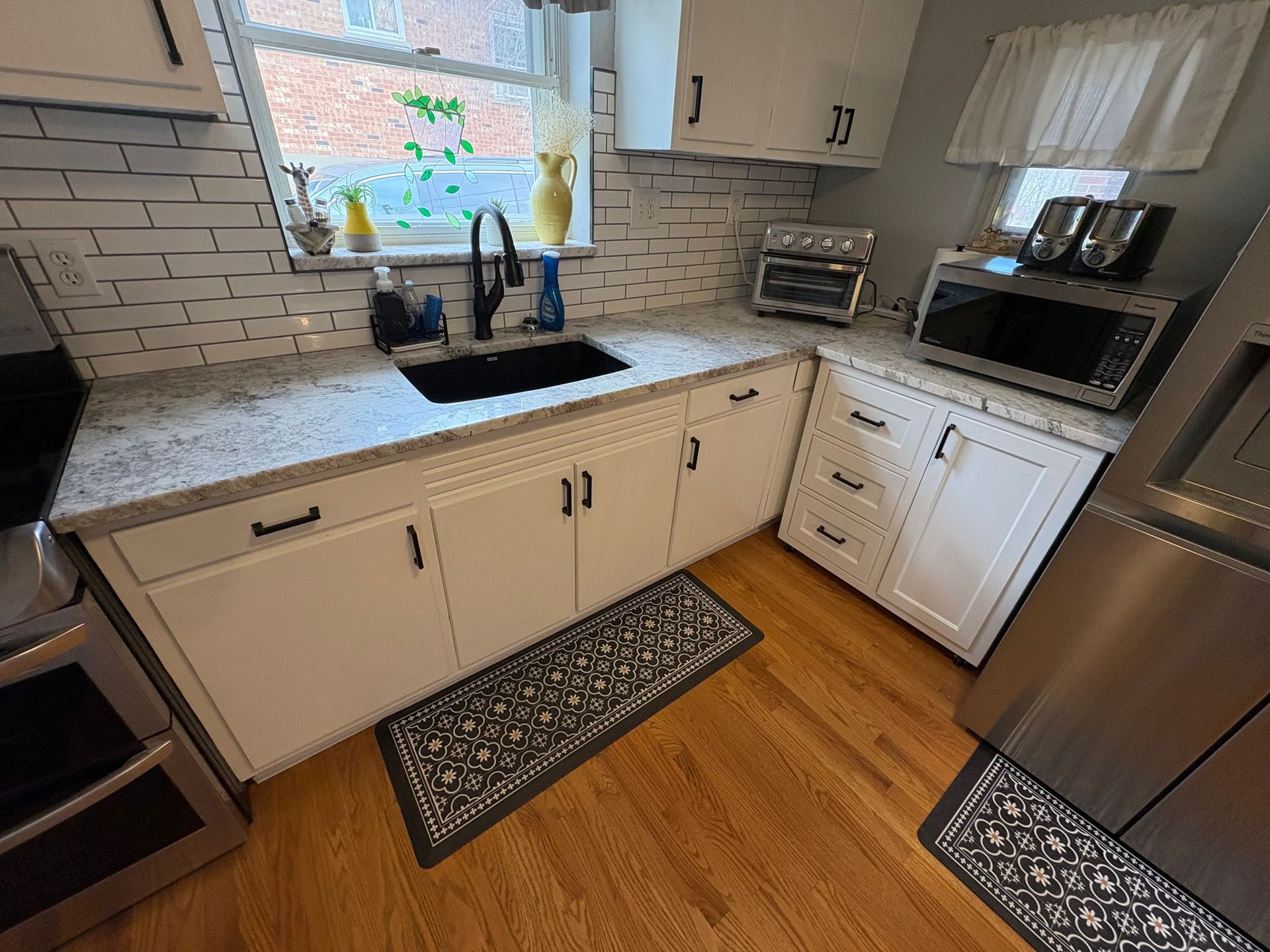 White kitchen with white cabinets, granite countertops, and stainless steel appliances.