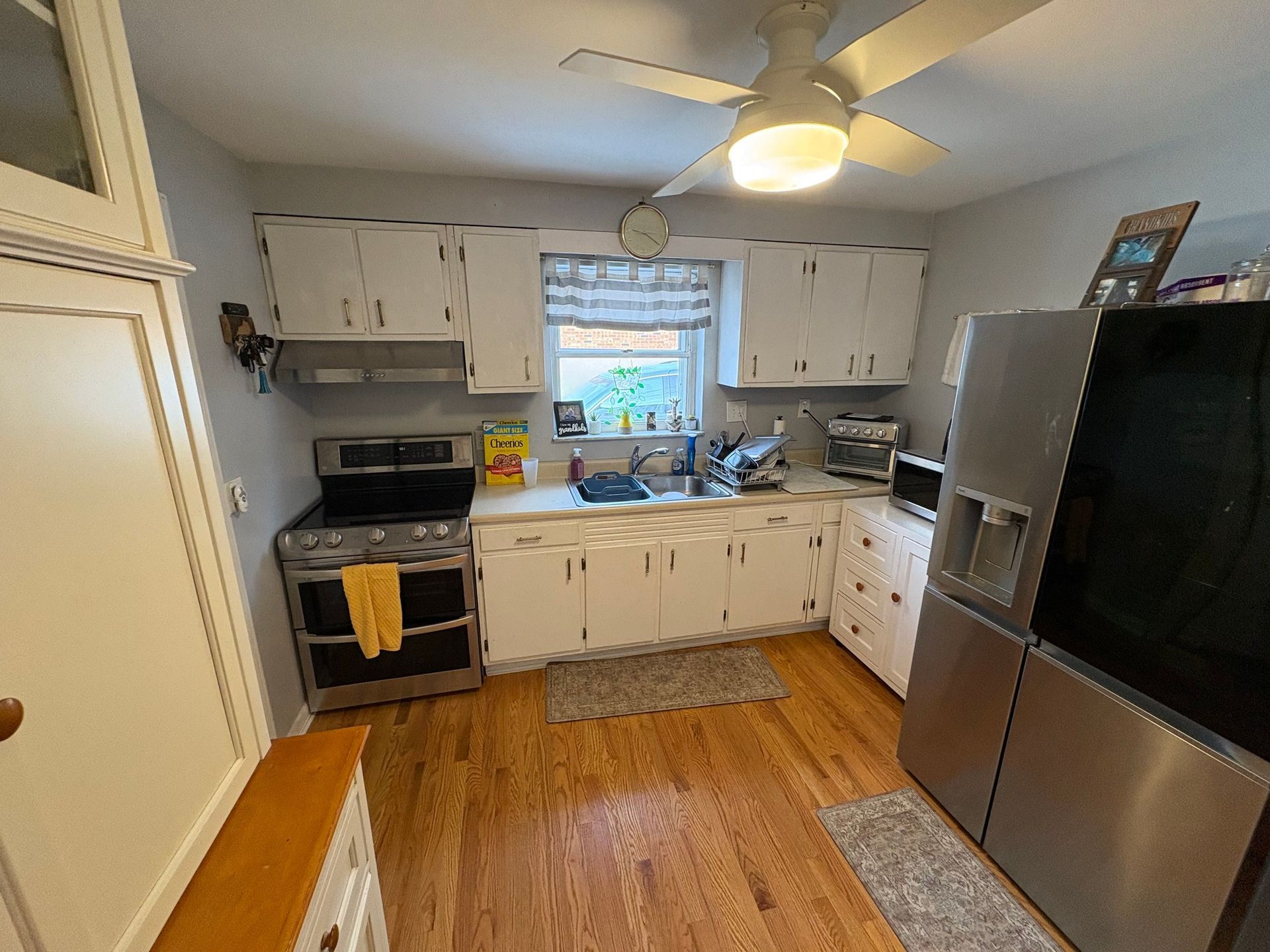 Kitchen with white cabinets, stainless steel appliances, and wooden floor.