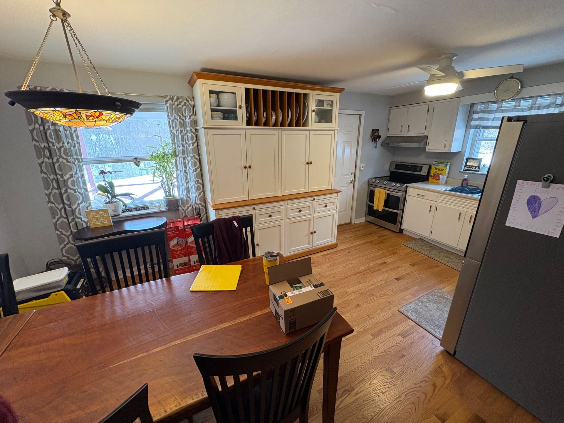 Dining room with wood table, hutch, and kitchen visible.