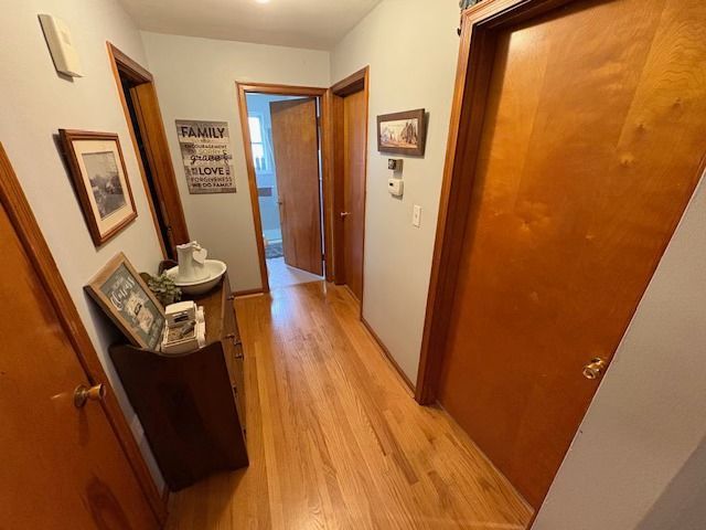 Hallway with wood floors, brown doors, and a wooden dresser with decor.