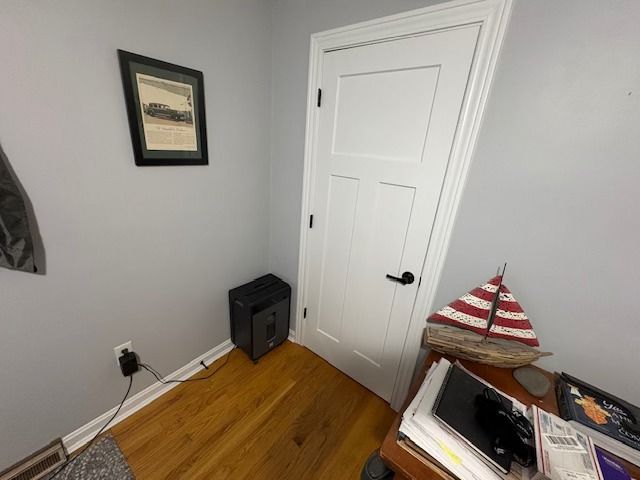 Small room with a white door, desk, and a framed picture. A heater sits on the floor.