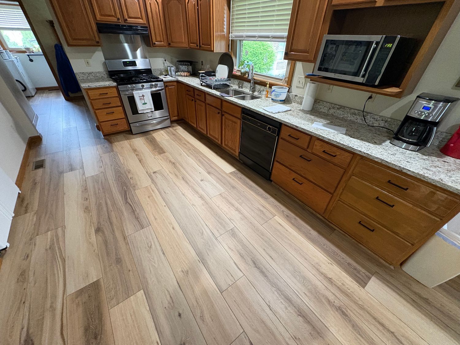 Kitchen with wooden cabinets, stainless steel appliances, and light wood flooring.
