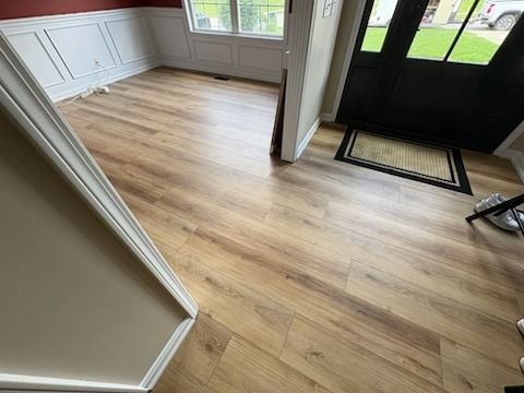 Wooden floor with open doorway and entry mat.