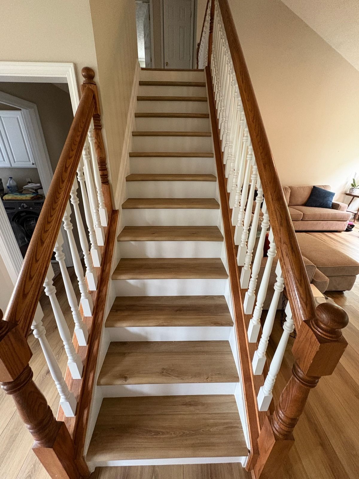 Wooden staircase with white banisters and wood handrails leading upwards to a door.