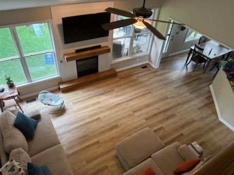 High-angle view of a living room with wood flooring, a fireplace, and a light-colored sectional sofa.