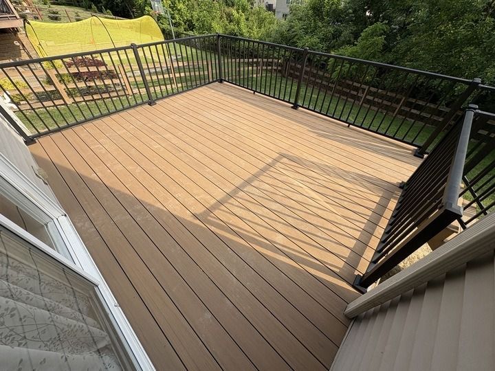 Outdoor composite deck with black railing; sunlight and shadows create patterns.