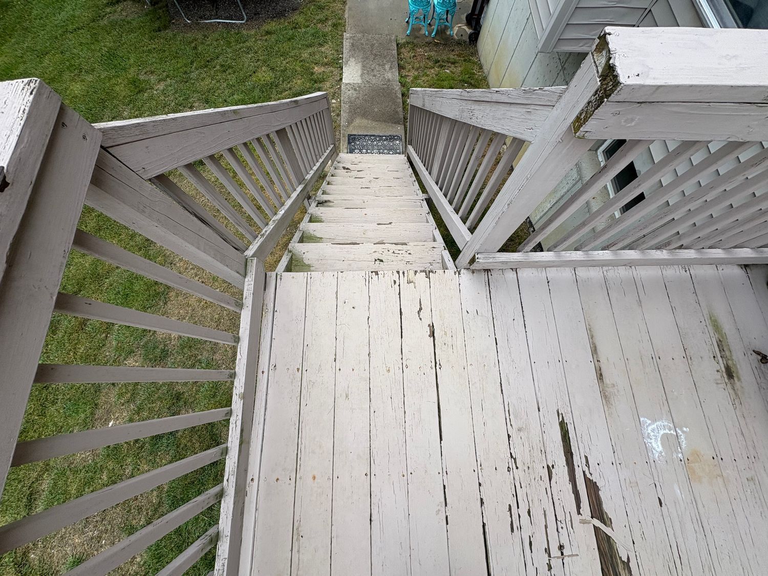 Overhead view of weathered, gray painted wooden stairs leading down from a porch.